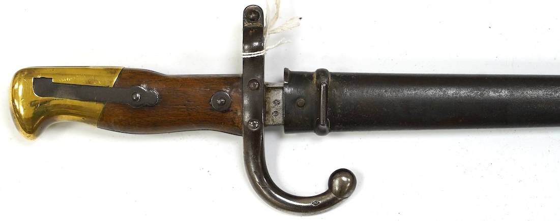 An 1875 French T-section bayonet in its steel scabbard for a Gras rifle, with engraving in French to the top of the blade. Condition - good